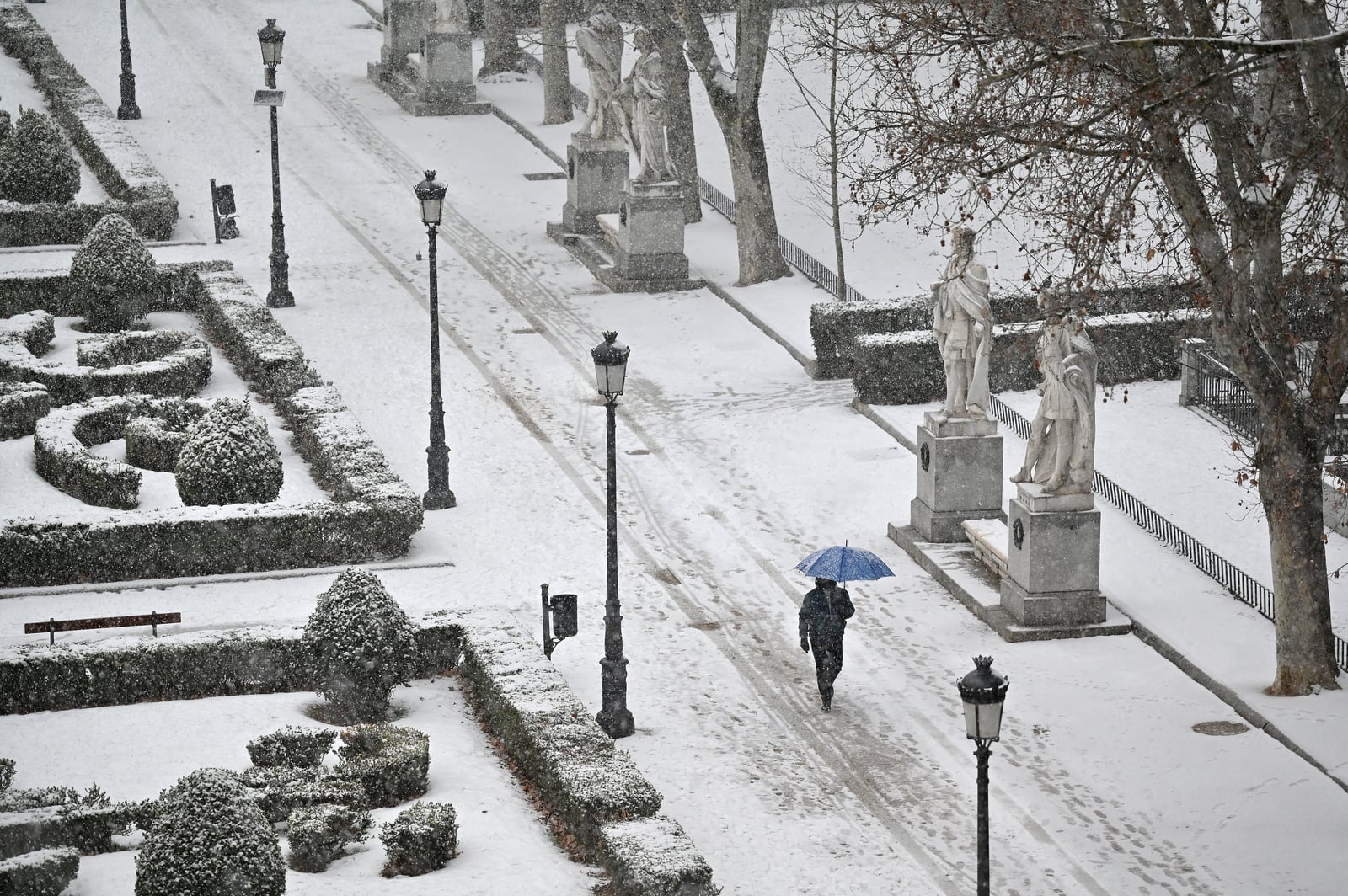 🇪🇸 Un hombre camina en la nieve a lo largo de los jardines de Sabatini frente al Palacio Real de Madrid, España. Foto: NIÑOS GABRIEL / AFP